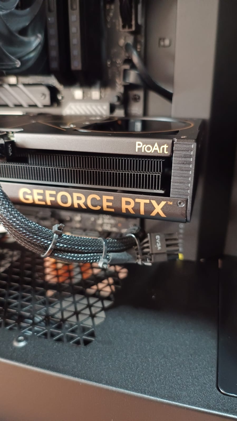 Primer plano de una tarjeta gráfica GeForce RTX ProArt instalada, con cable de alimentación mallado
