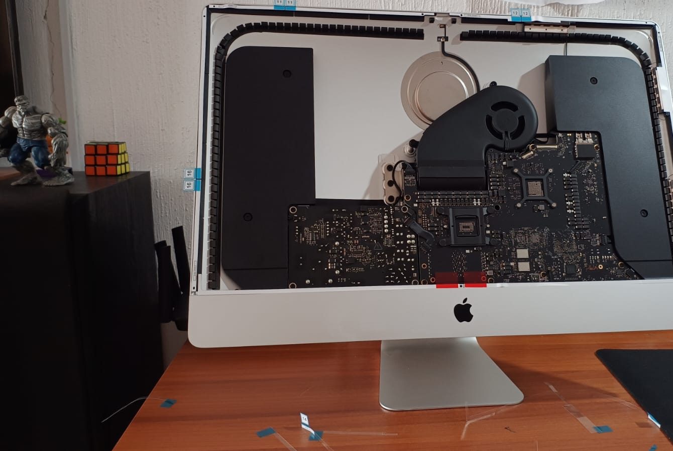 iMac abierta sin pantalla en el taller, con la placa lógica y el ventilador expuestos durante la reparación