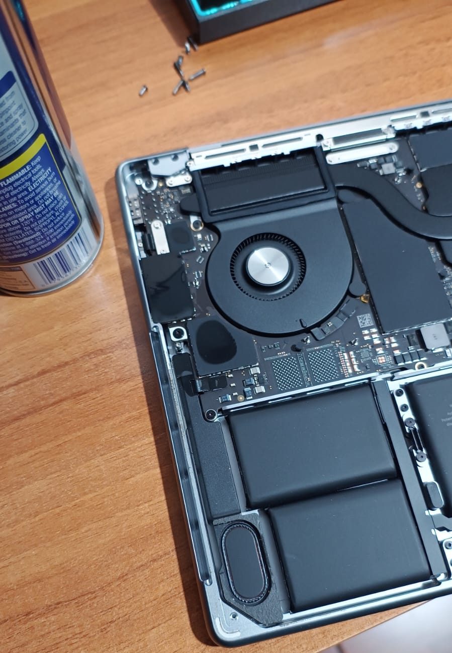 MacBook Pro abierta en el taller, con batería, ventilador y placa lógica a la vista durante una reparación