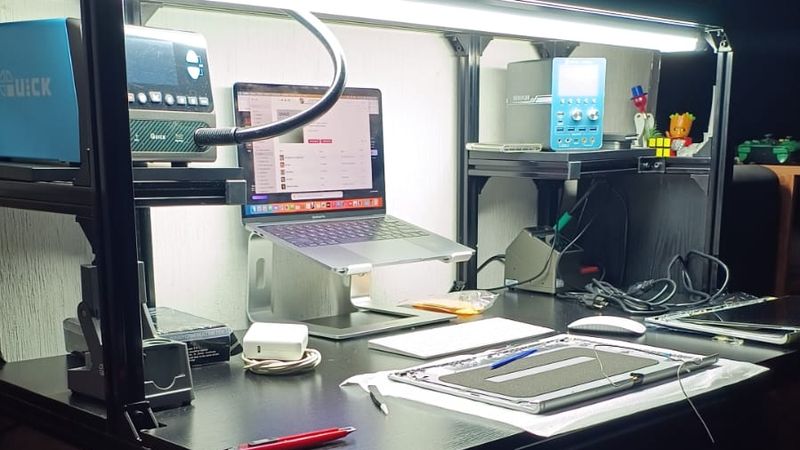 Estación de trabajo del taller WFG Solutions: mesa con iluminación LED, instrumentos de medición y una MacBook en reparación